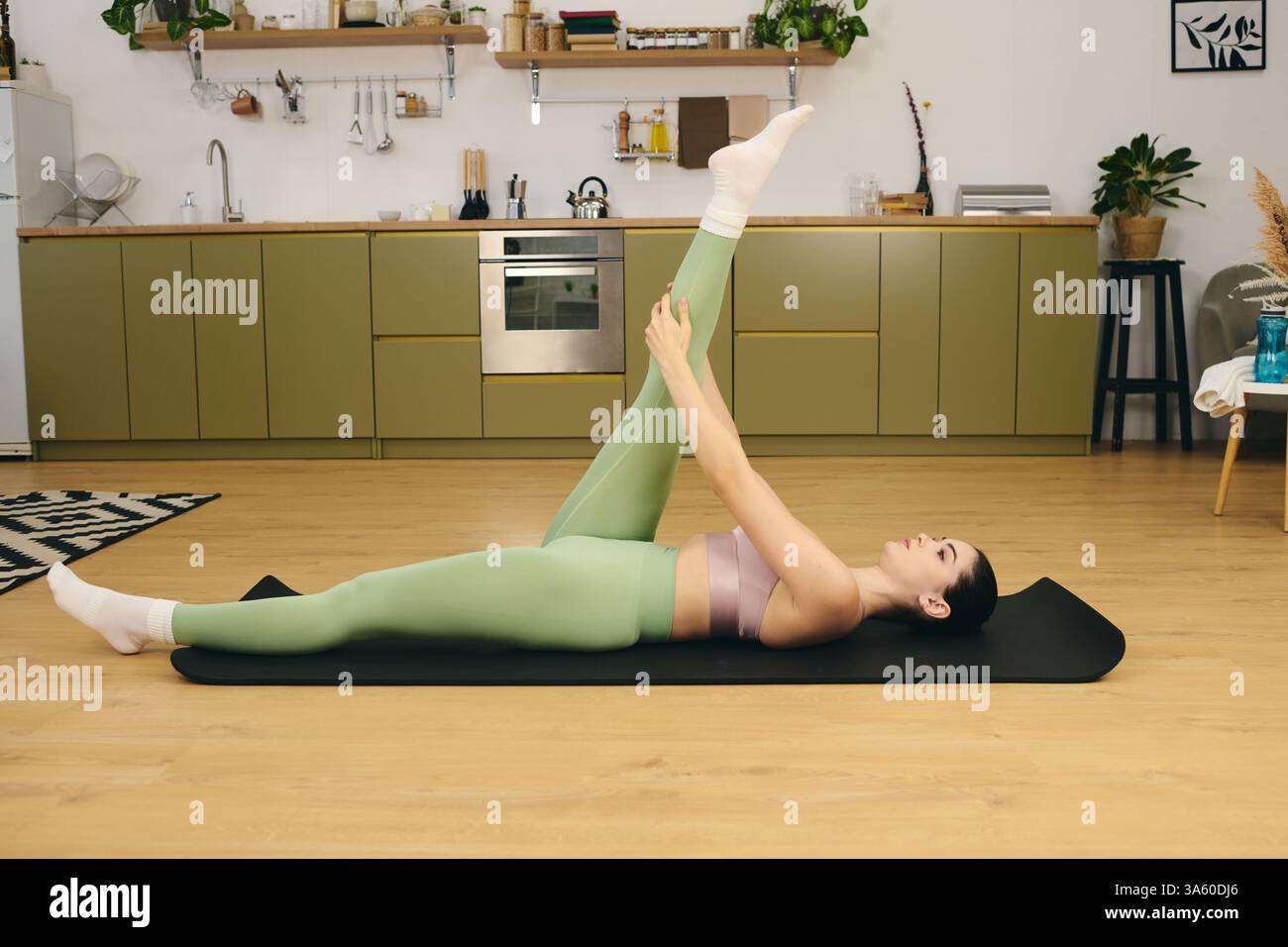 A fit woman stretches on a yoga mat in her stylish home Stock Photo - Alamy