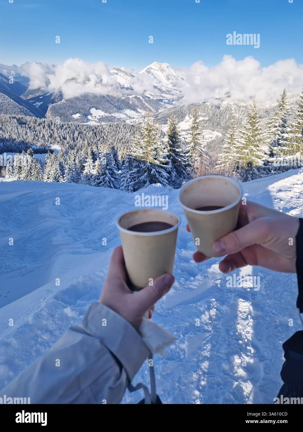 Two friends hands holding paper cups filled with hot chocolate beverage on the top of the a snowy mountain. Winter activity and vacation enjoyment con - Smartphone Captured Stock Image