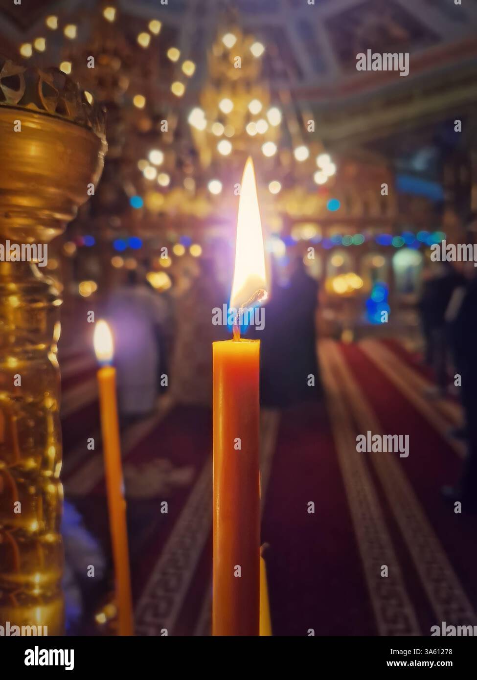 Closeup of a lit candle on the candelabra inside a Christian Orthodox church. The burning flame is sharp and bright. Religious symbol for Easter or Ch - Smartphone Captured Stock Image