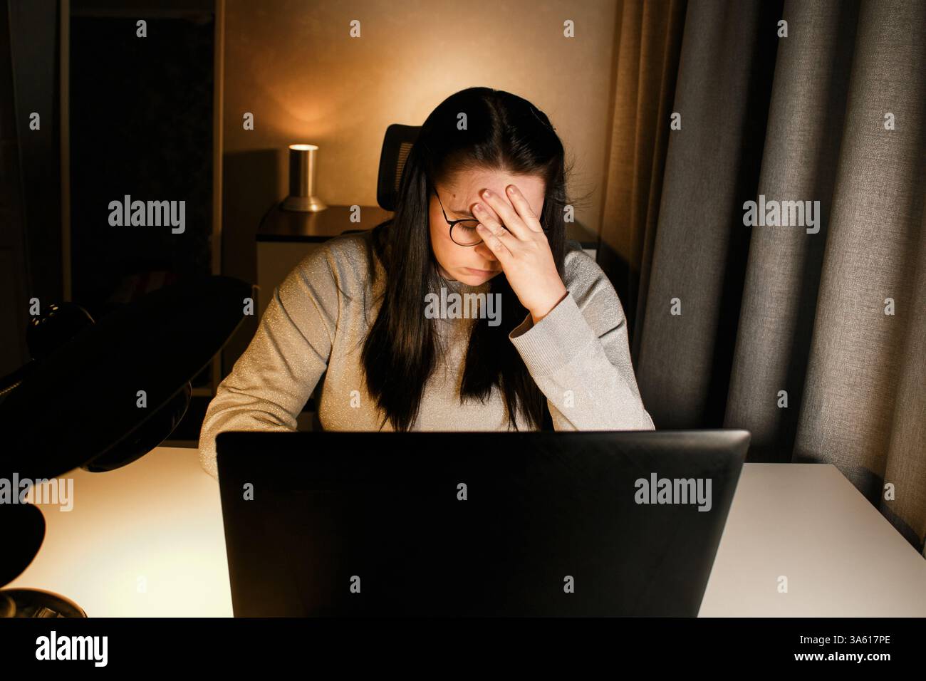 Tired woman working on computer touching her head because of headache ...
