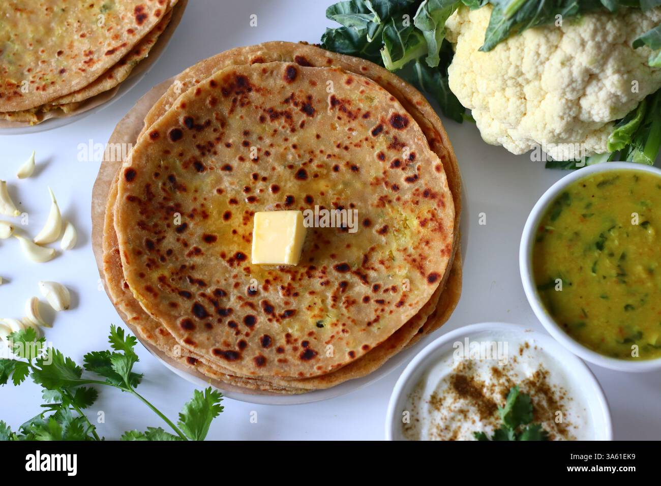 Gobi parathas served with masala raita and dal curry in bowls, shot ...