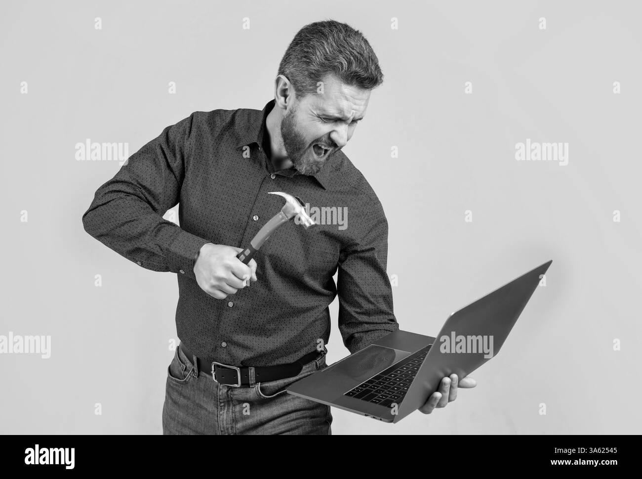Furious man break laptop hitting notebook with hammer grey background ...