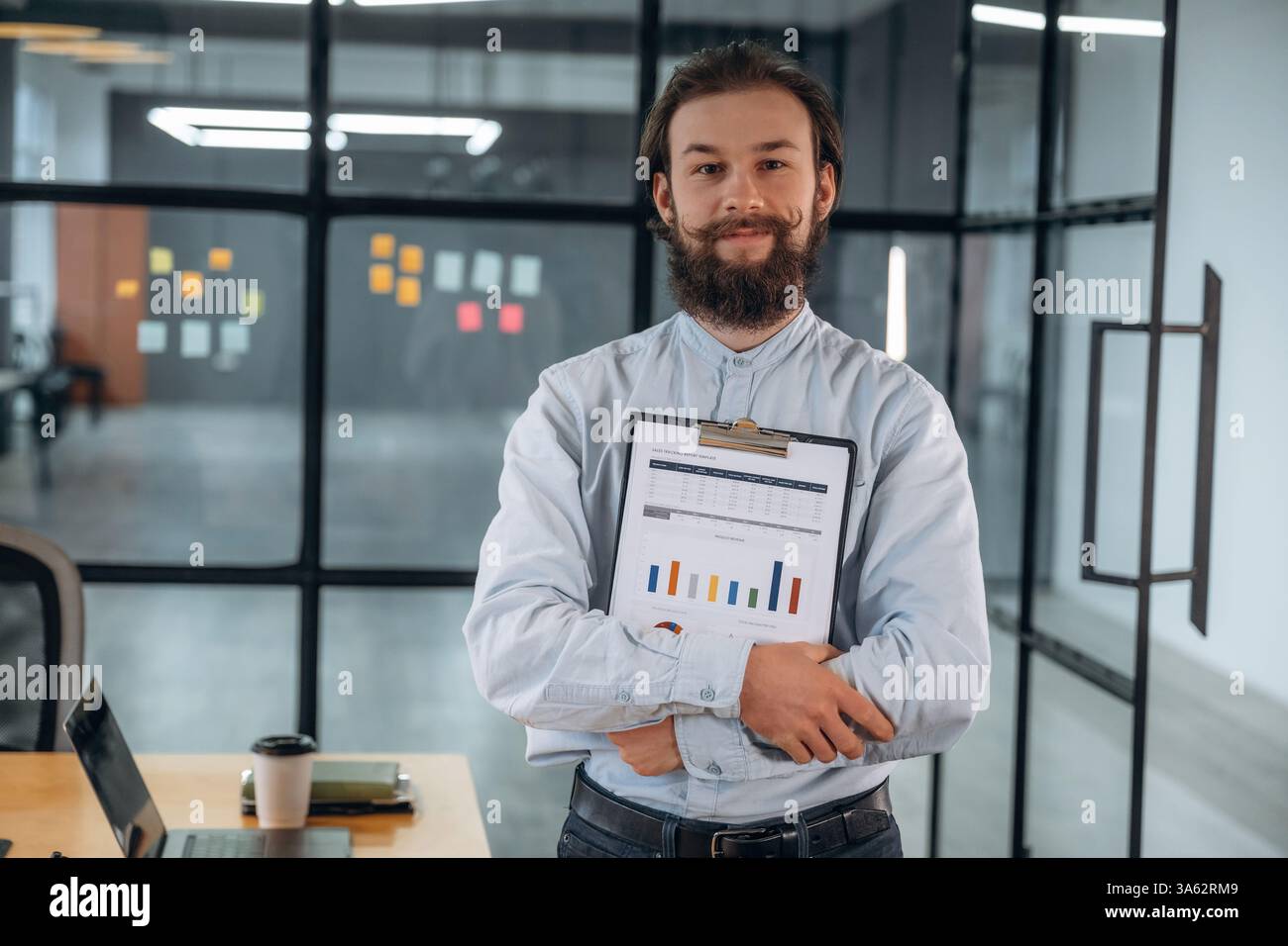 Standing, holding documents and smiling. Businessman is working in the office. Stock Photo