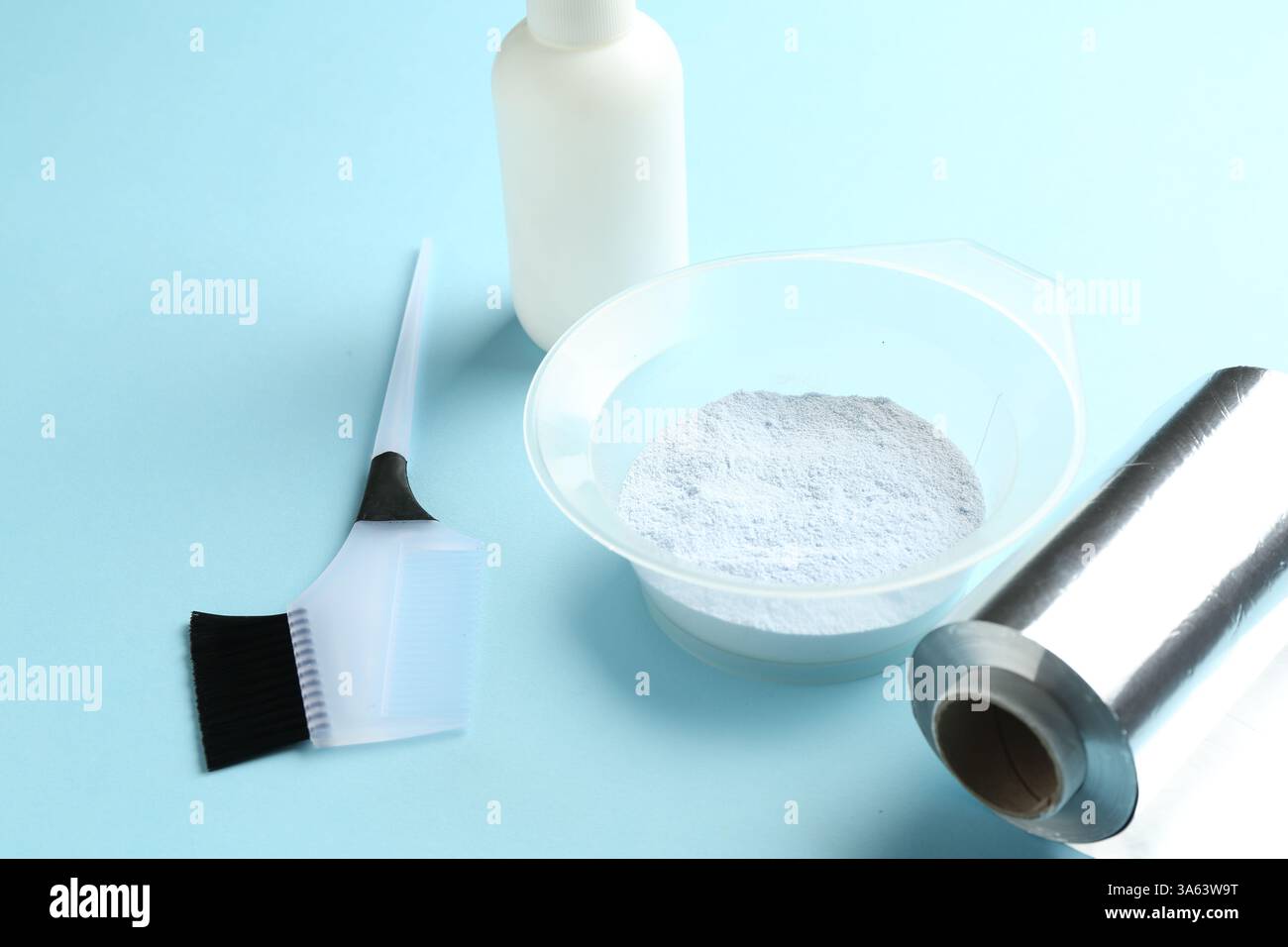 Bleaching powder and hairdresser's tools on light blue background ...