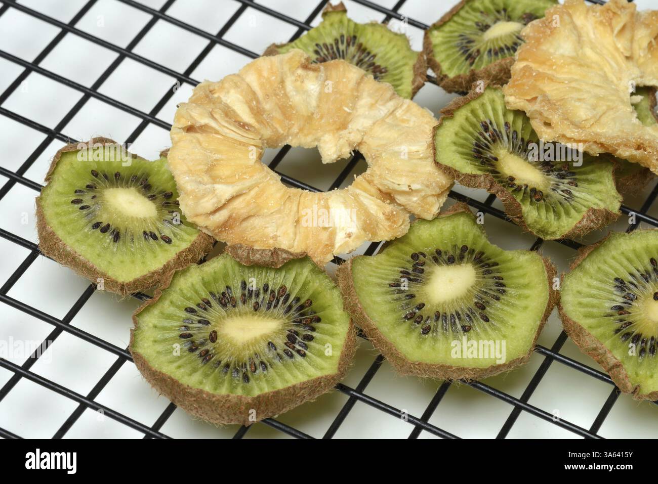Dried pineapple slices and dried kiwi slices on a wire rack Stock Photo