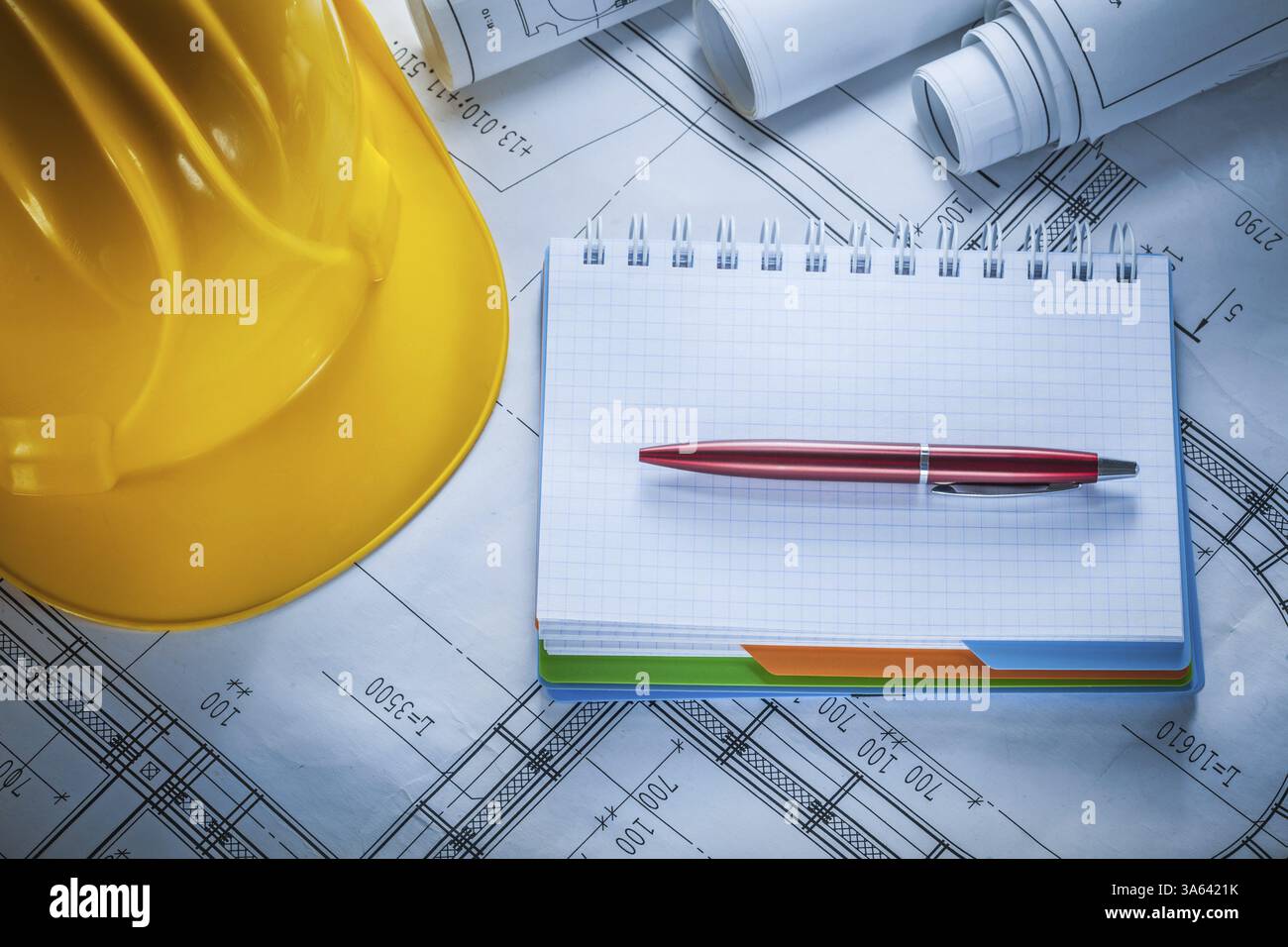 Hard hat checked notebook pen blueprints on construction drawing Stock Photo