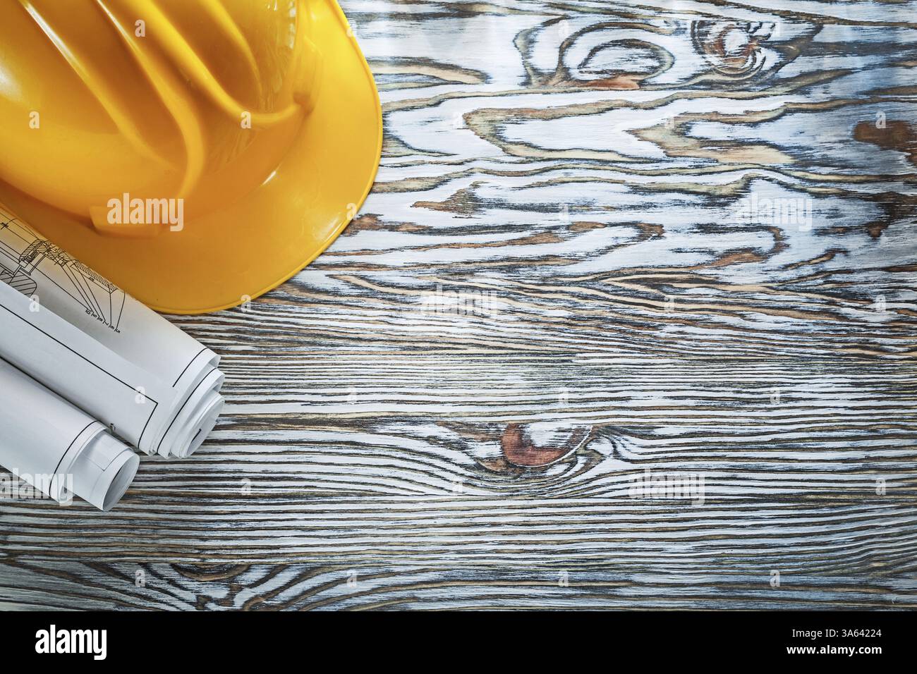 Rolled construction plans building helmet on vintage wooden board Stock Photo