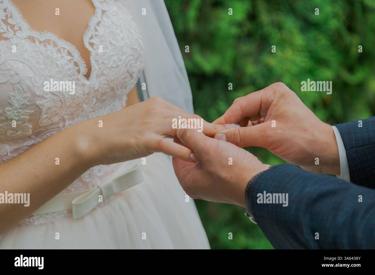 A handsome young groom puts on a ring to the bride on their wedding day ...