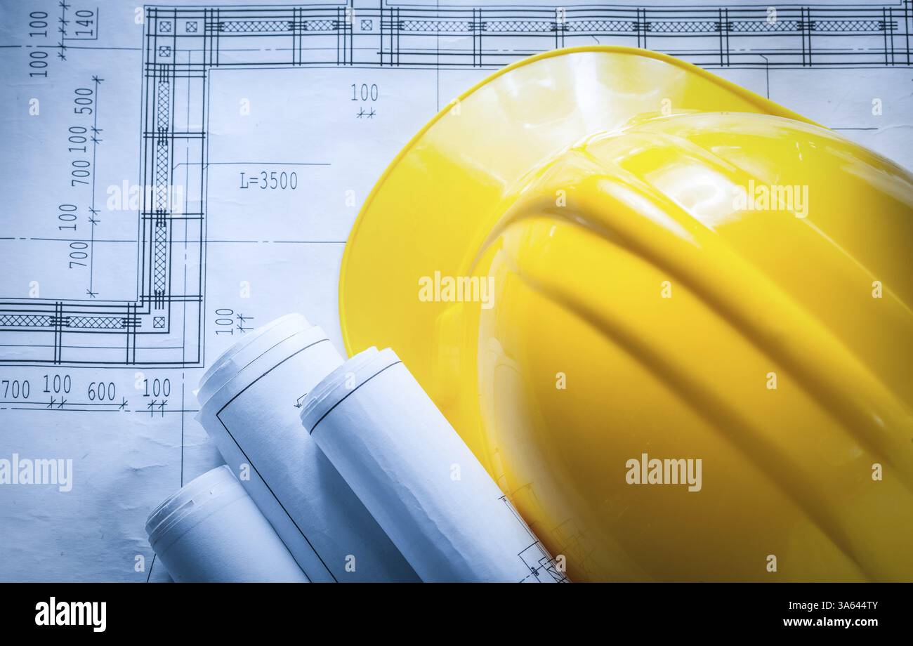 Building helmet rolled construction plans on blueprint Stock Photo - Alamy