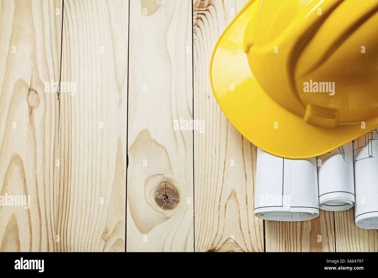 Rolled blueprints and yellow construction helmet on wood boards Stock ...