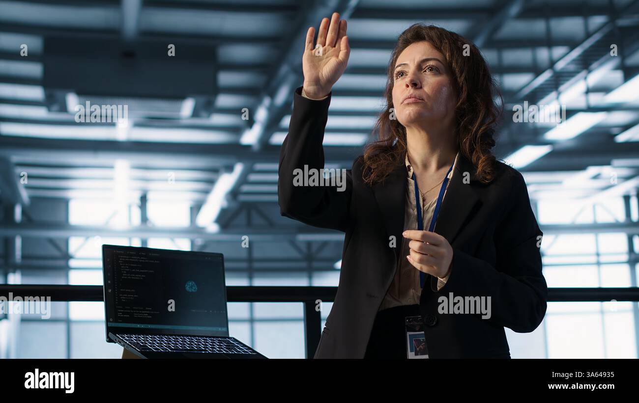 Technicians in high tech AI data center workspace looking at hologram visualization. Programmer working on securing server room hardware using AR artificial intelligence tech, camera A Stock Photo