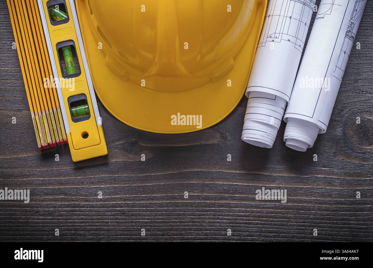 Rolls of blueprints construction level building helmet and wooden meter ...