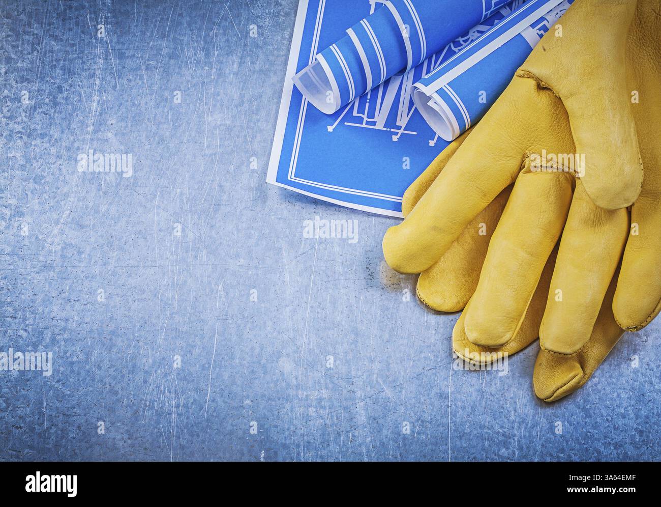 Composition of safety gloves blue rolled up blueprints Stock Photo - Alamy