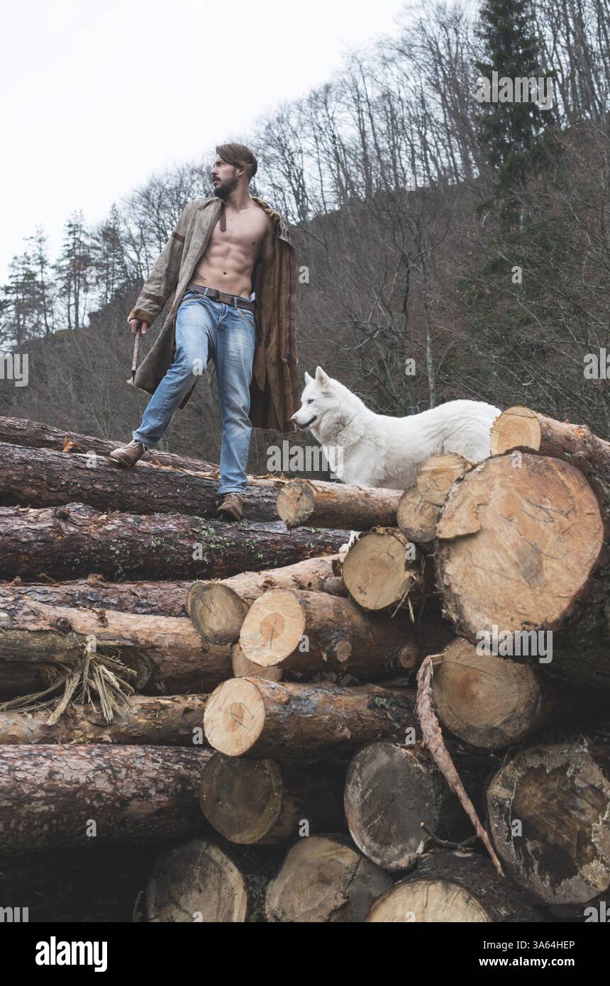 Young man and dog on logs in the forest. Fashion style Stock Photo - Alamy
