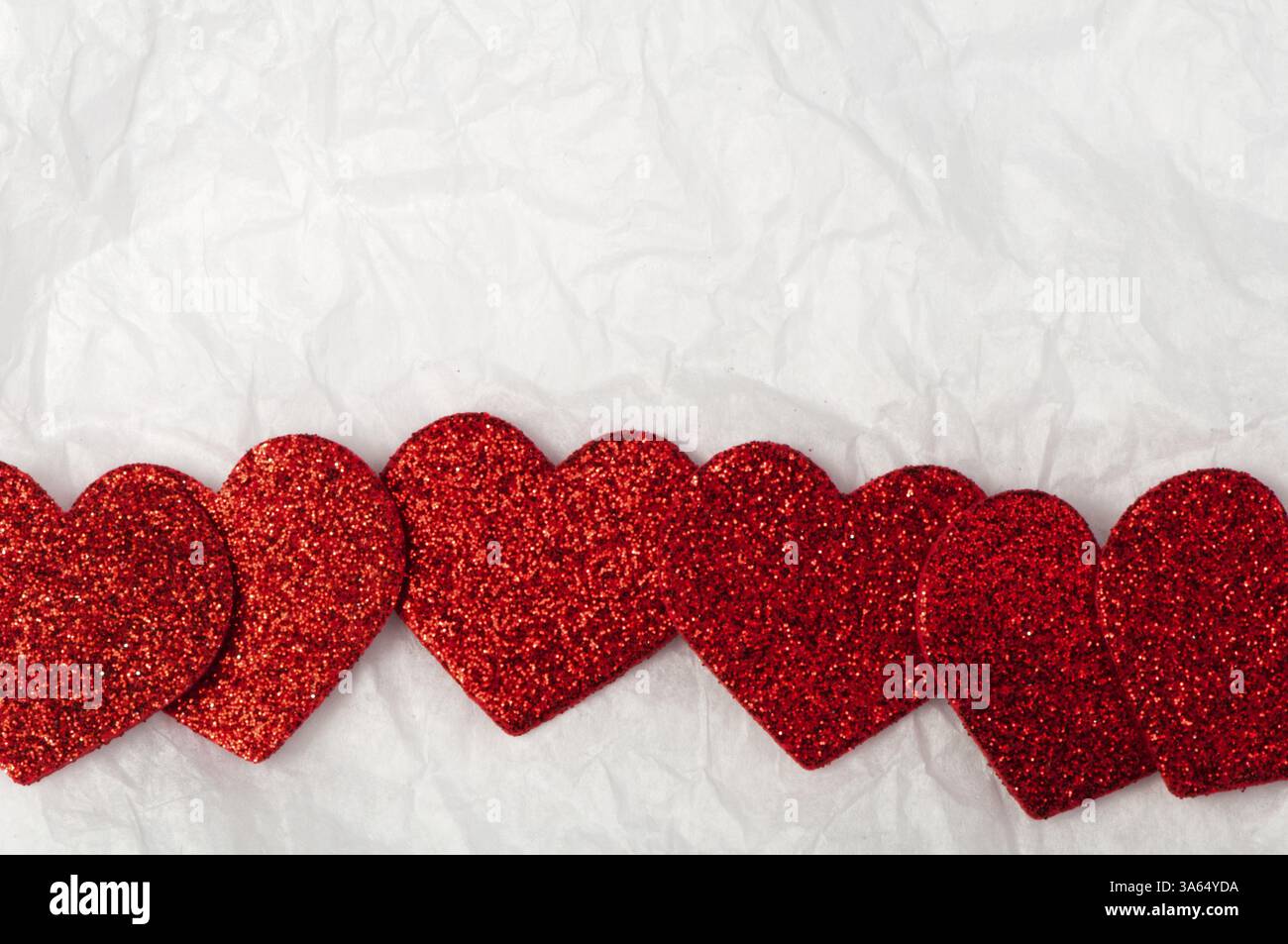 Shiny red hearts on white crumpled paper Stock Photo - Alamy
