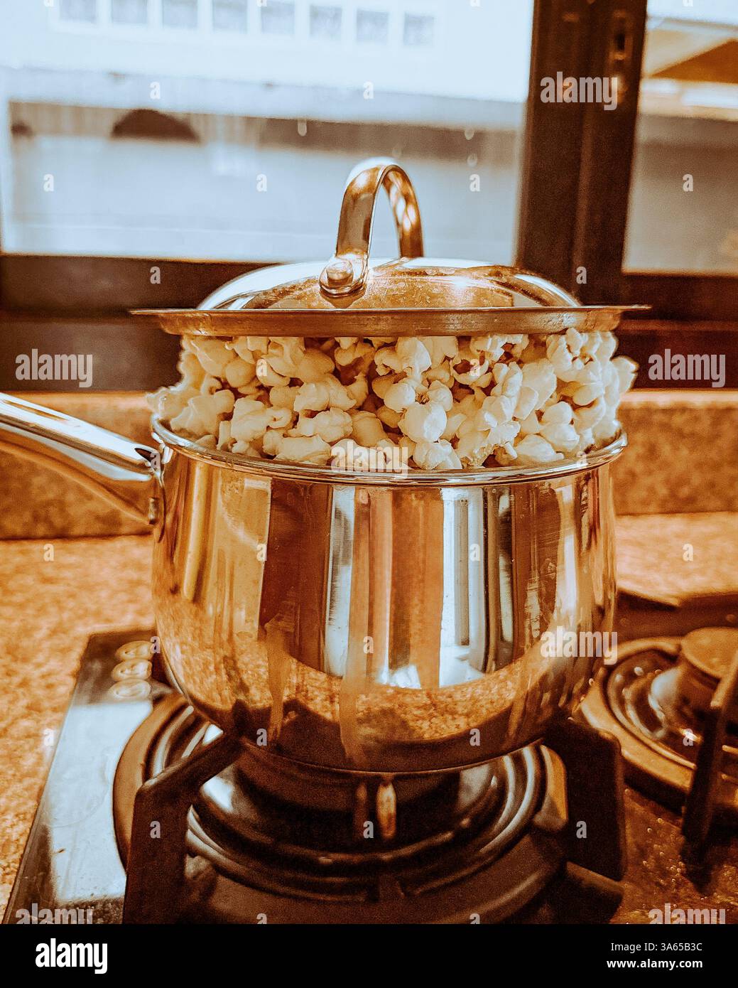 Overflowing popcorn pot on a stovetop 2 A stainless steel pot filled ...