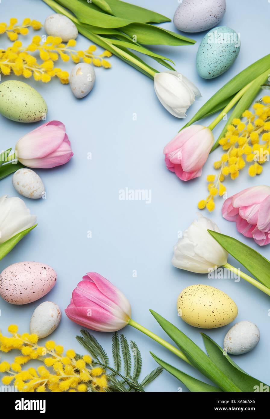 Easter eggs and tulips creating a frame on light blue background for ...