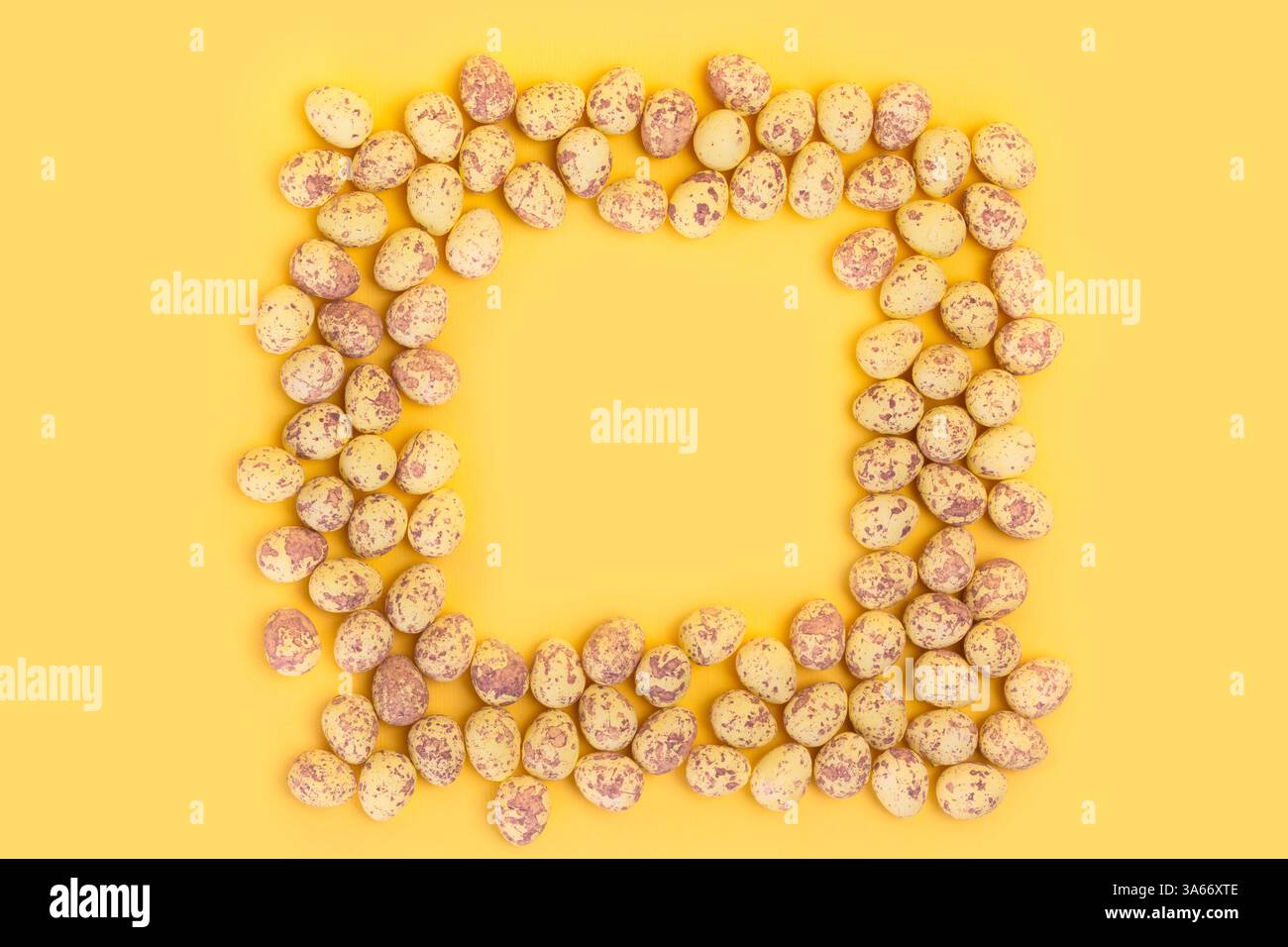 Small quail eggs shaped into square isolated on plain yellow background Stock Photo