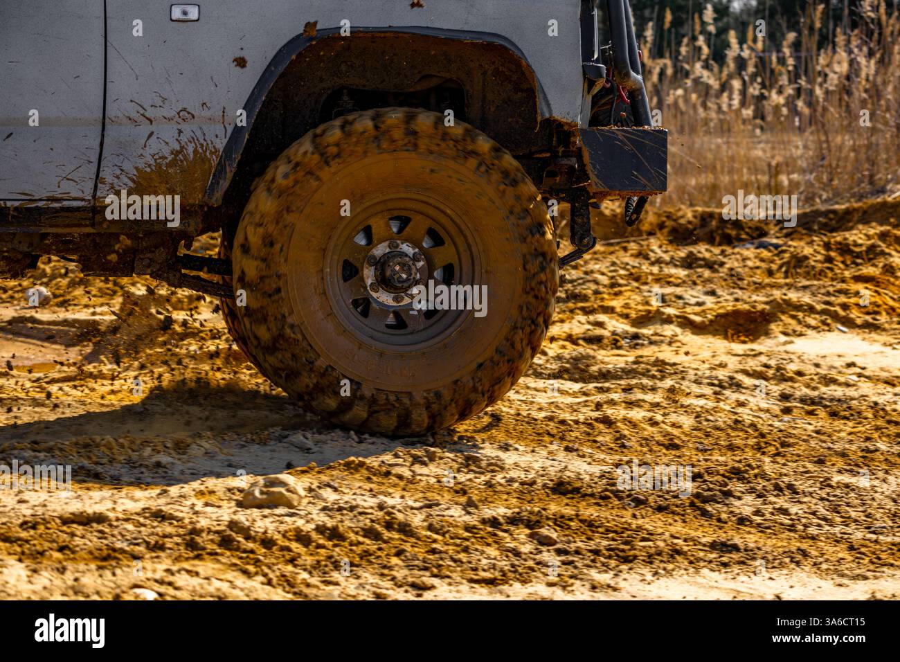 Off-road vehicle tires covered in mud and sand, car crossing a ditch ...