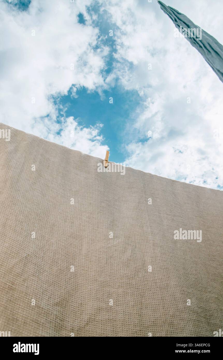 Low angle linen fabrics air drying on clothesline with cloudy sky ...
