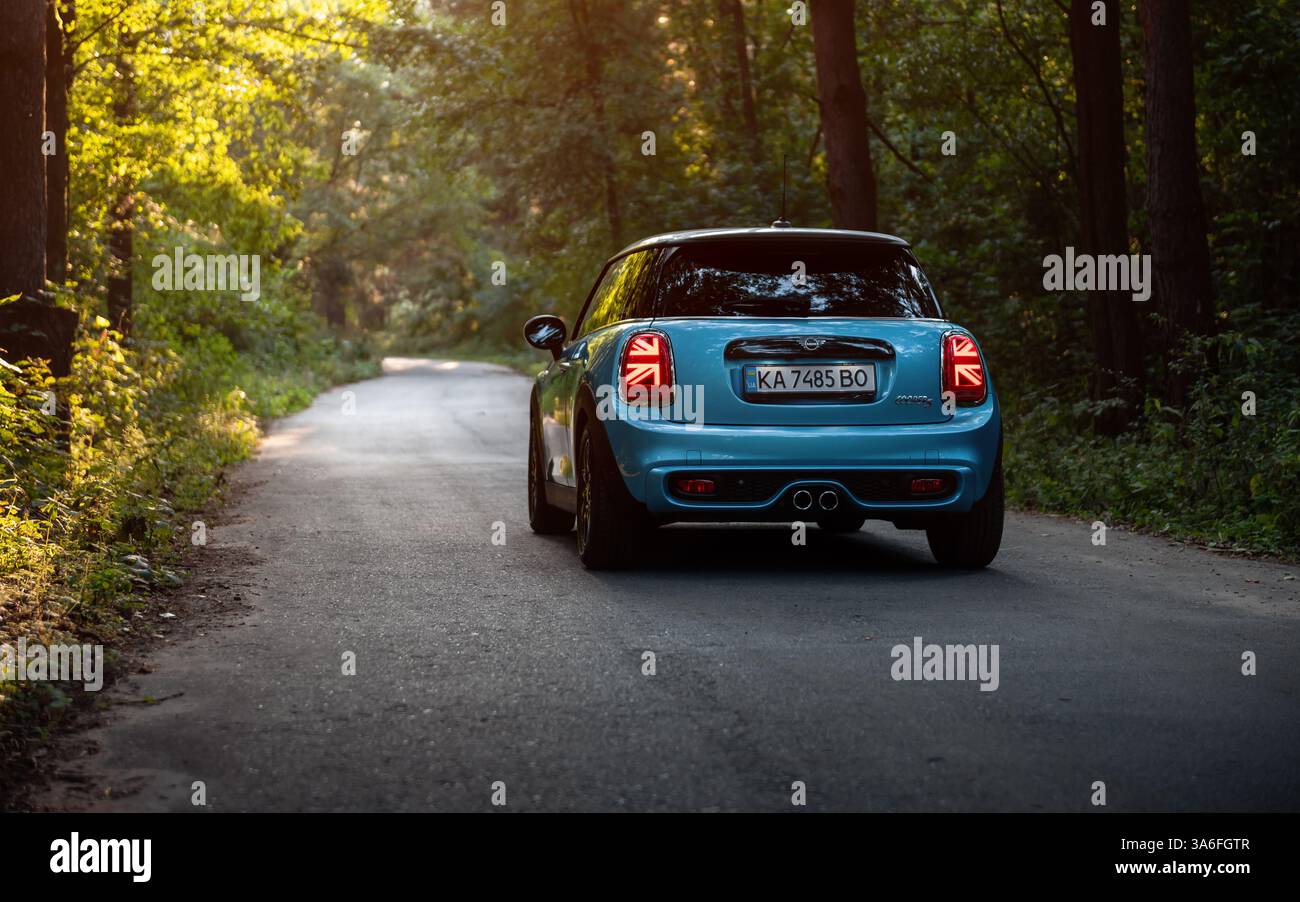 Blue Mini Cooper on a forest road. Rear view of blue compact hatchback ...