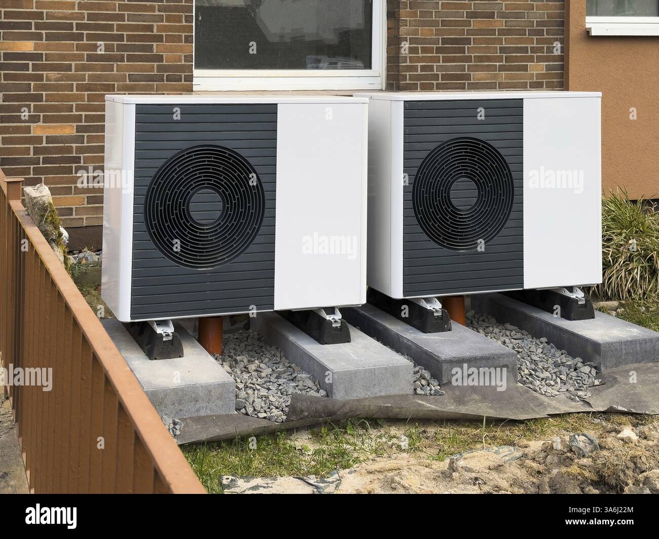 2 heat pumps are installed on an apartment block in a front garden ...
