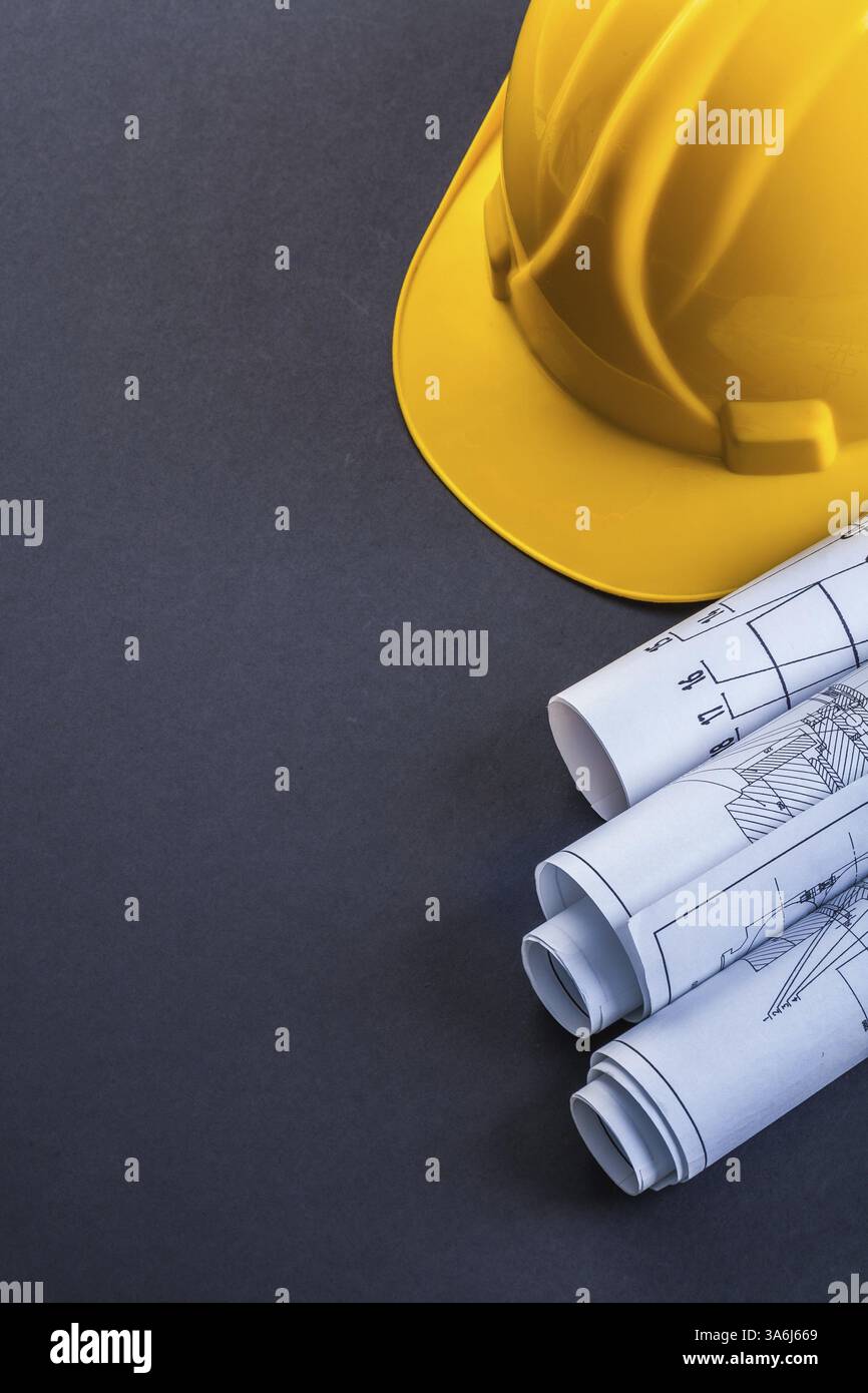 Rolls of blueprint and yellow helmet on black background Stock Photo ...
