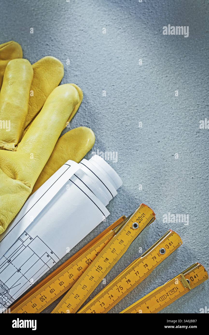 Safety gloves rolled blueprints wooden meter on concrete background ...