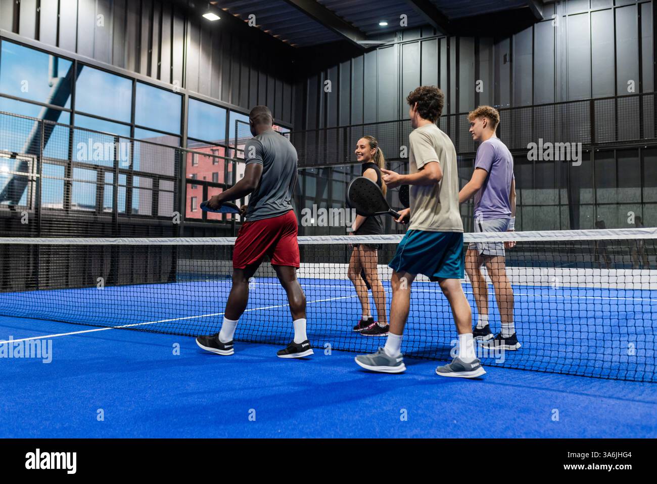 Group of friends playing padel tennis indoors, enjoying active ...
