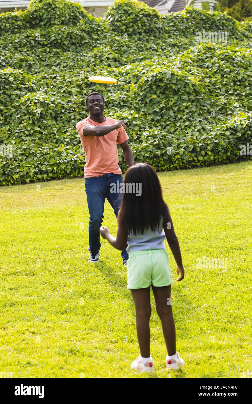 African American dad and daughter playing frisbee in backyard, enjoying sunny day Stock Photo