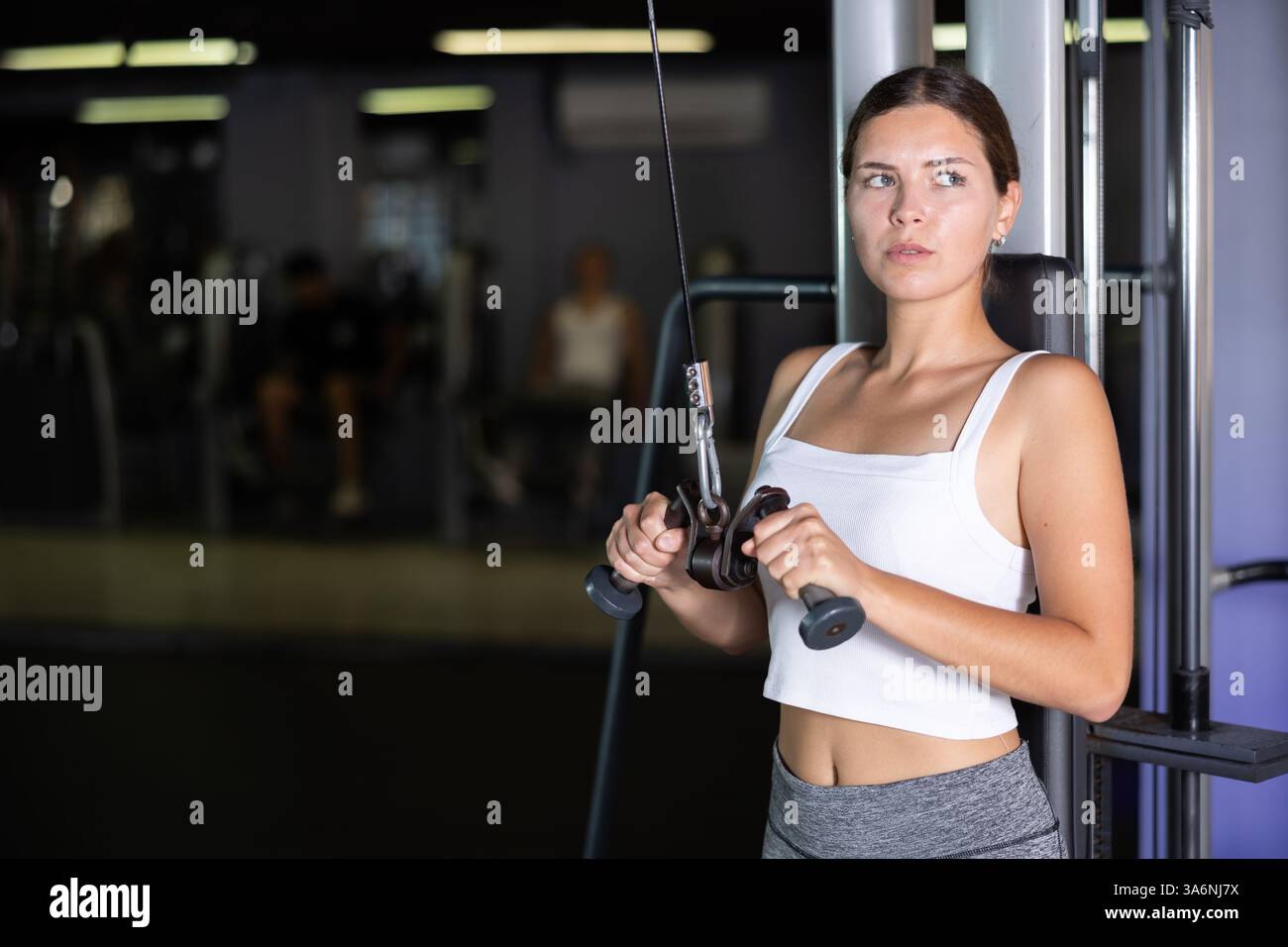 Athletic girl work out muscles of arms and shoulders on rope loop ...