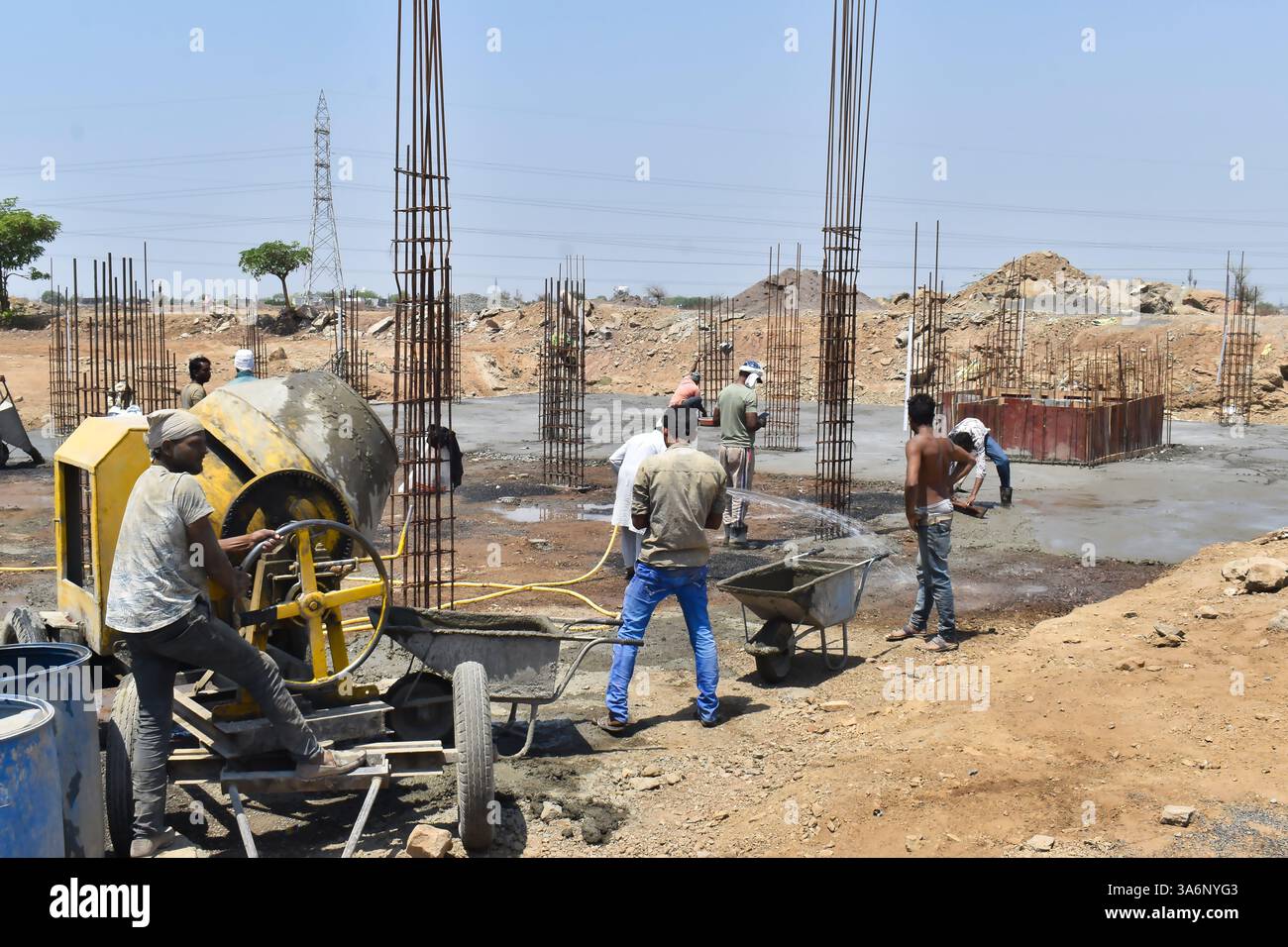 Construction workers at a building site using a concrete mixer and ...