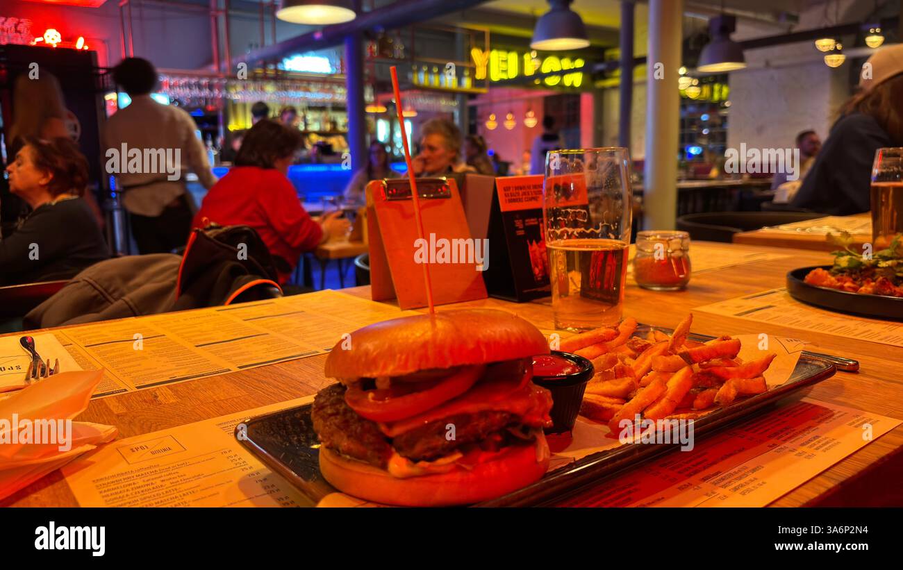 Large burger and fries in a trendy restaurant cafe. Fine dining designer chef food. Steak dinner with salad and chips - Smartphone Captured Stock Image