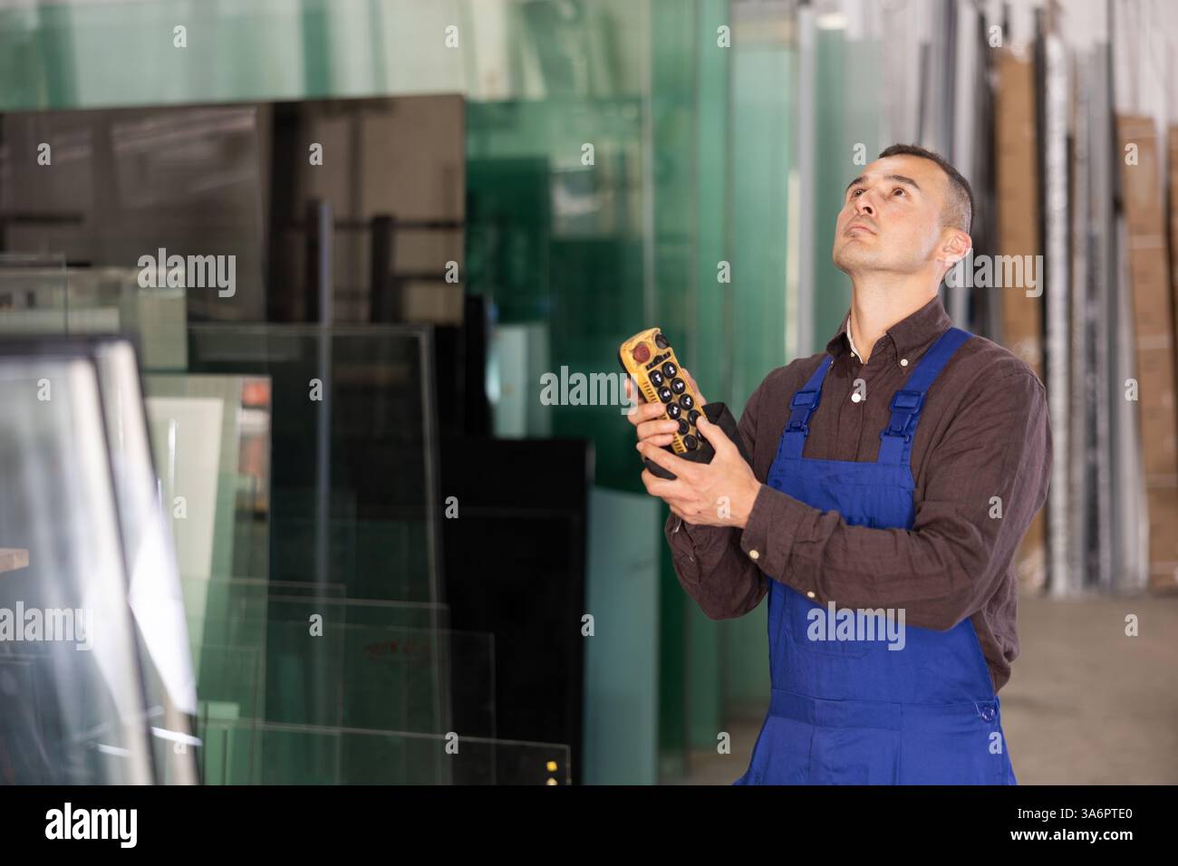 Worker using remote control to operate machinery in glass workshop Stock Photo