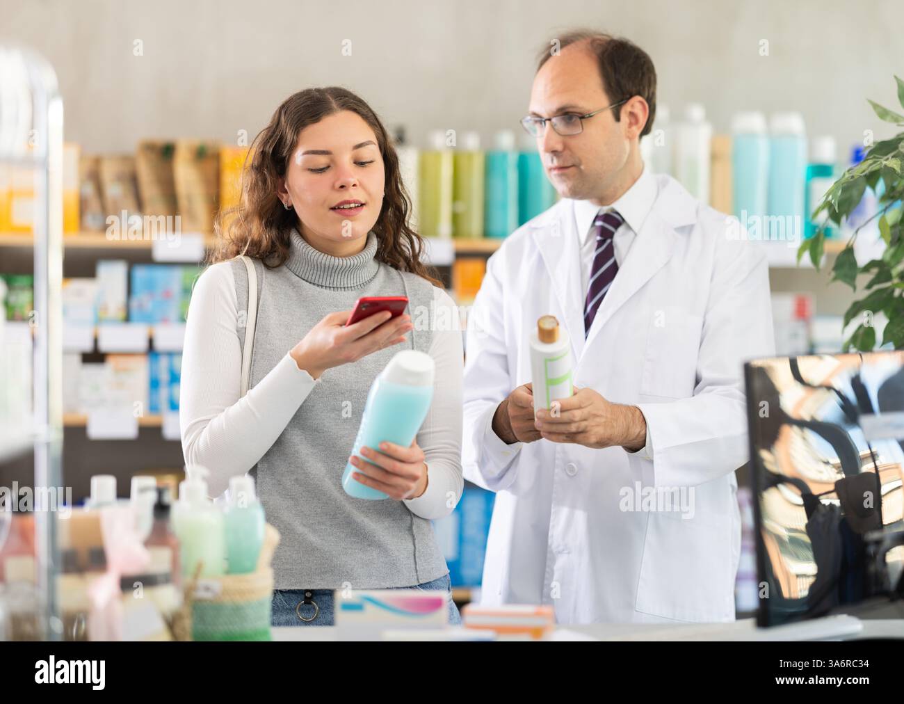 Male pharmacist and female customer scan code on medicated shampoo ...