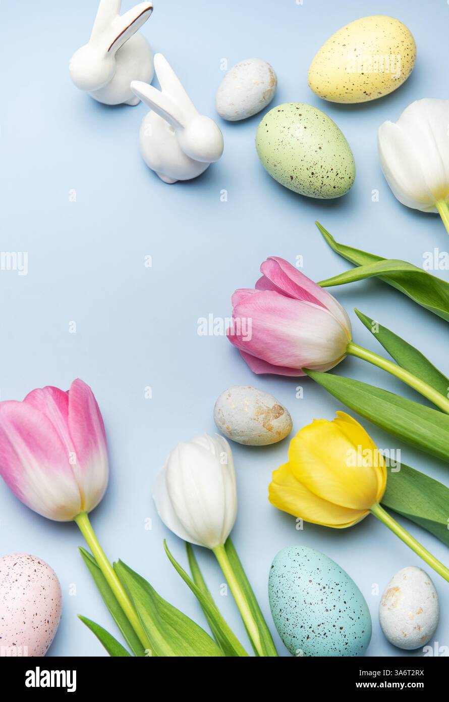 Easter eggs and colorful tulips are arranged on a light blue background ...