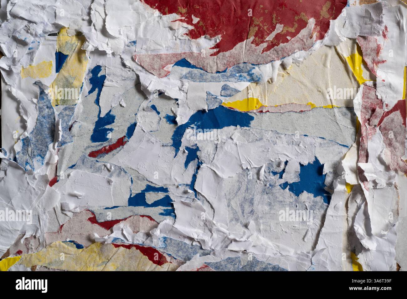 Dirty wall texture with peeled white, red, blue and yellow paper Stock Photo
