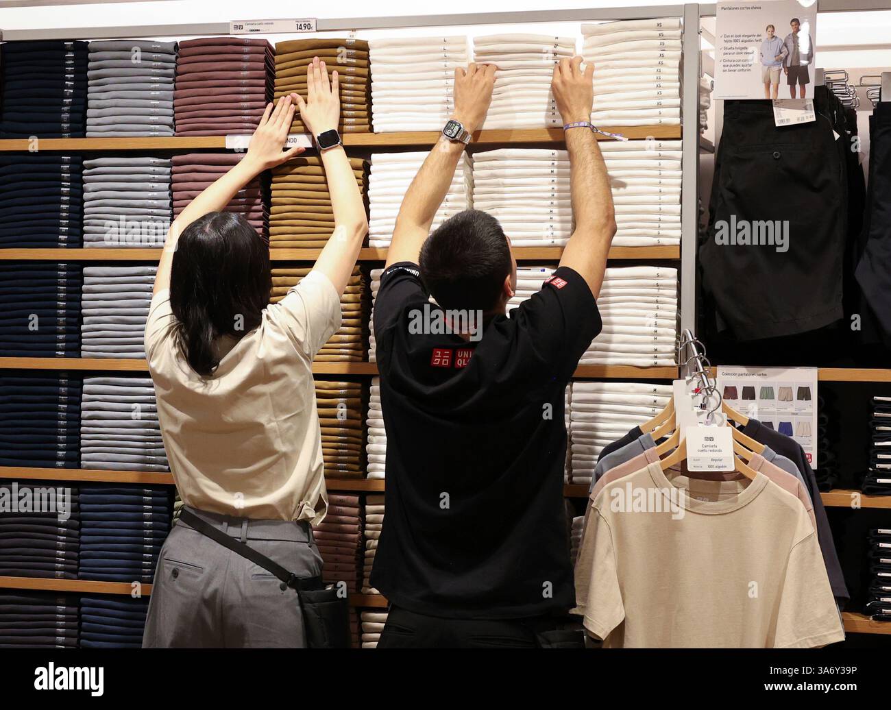 Several sales clerks place clothes in the new Uniqlo flagship store, on ...