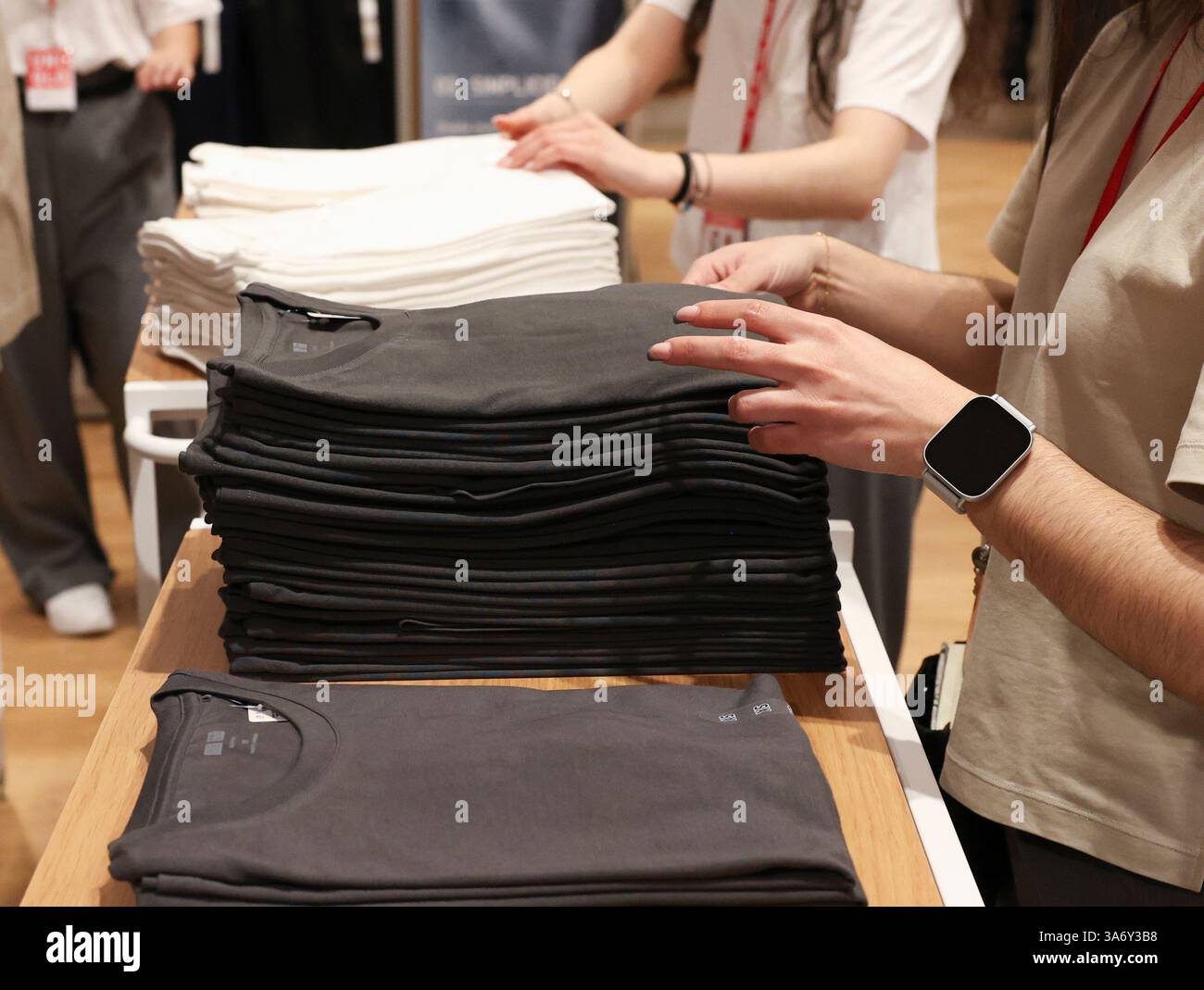 Several sales clerks place clothes in the new Uniqlo flagship store, on ...