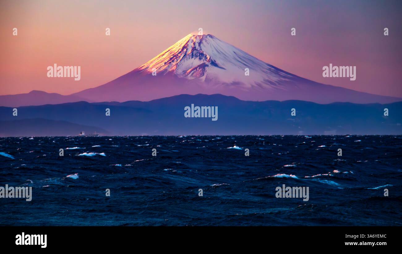 From the west coast of Izu Oshima in Tokyo, you can see a spectacular view of Mt.Fuji shining in the setting sun across the rough waves of Sagami Bay. Stock Photo