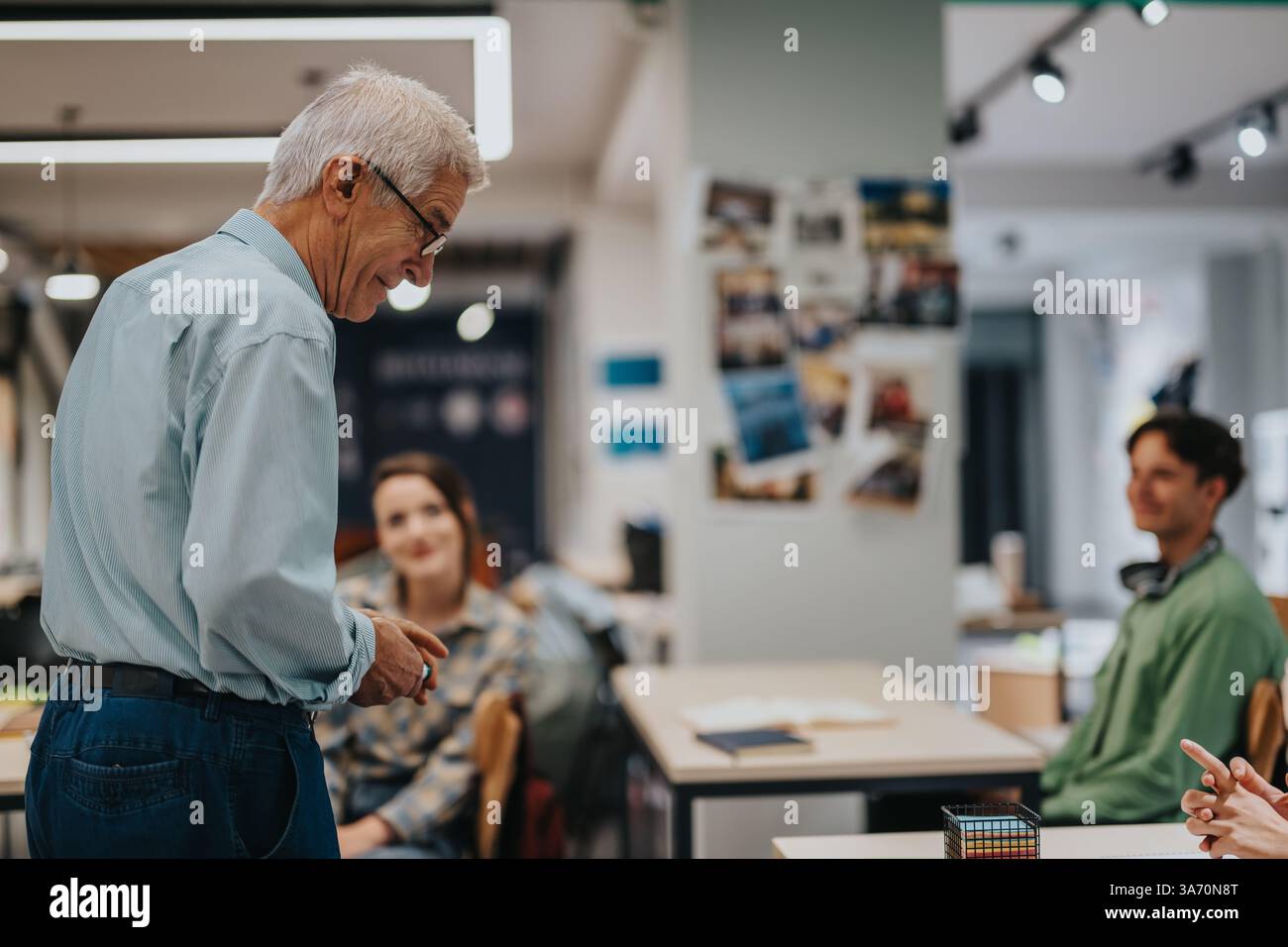 Elderly professor engaging with students in a modern classroom setting Stock Photo