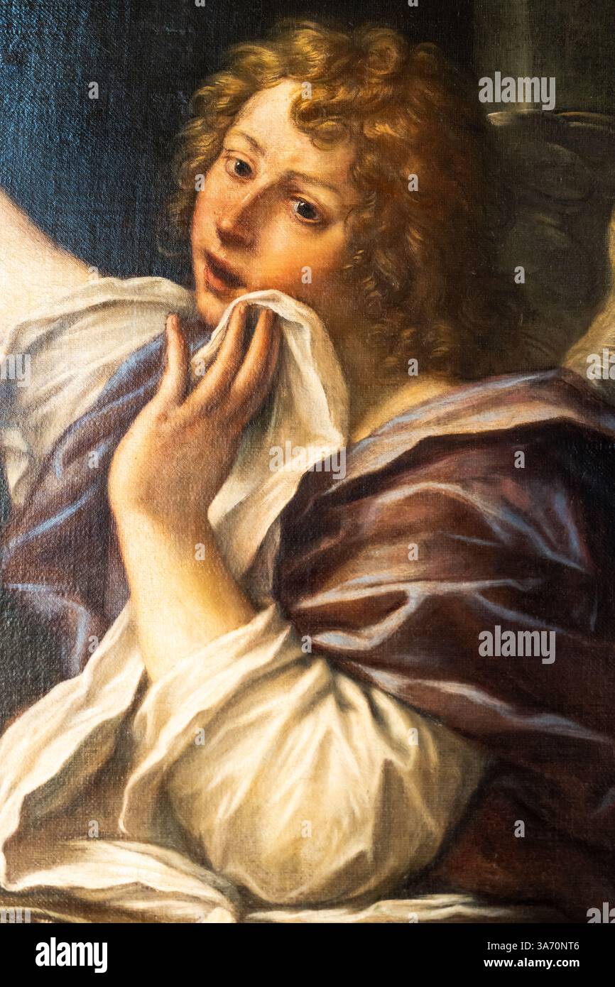 Close-up on old painting portraiting a blond angel with curly hair rubbing a cloth on his face Stock Photo