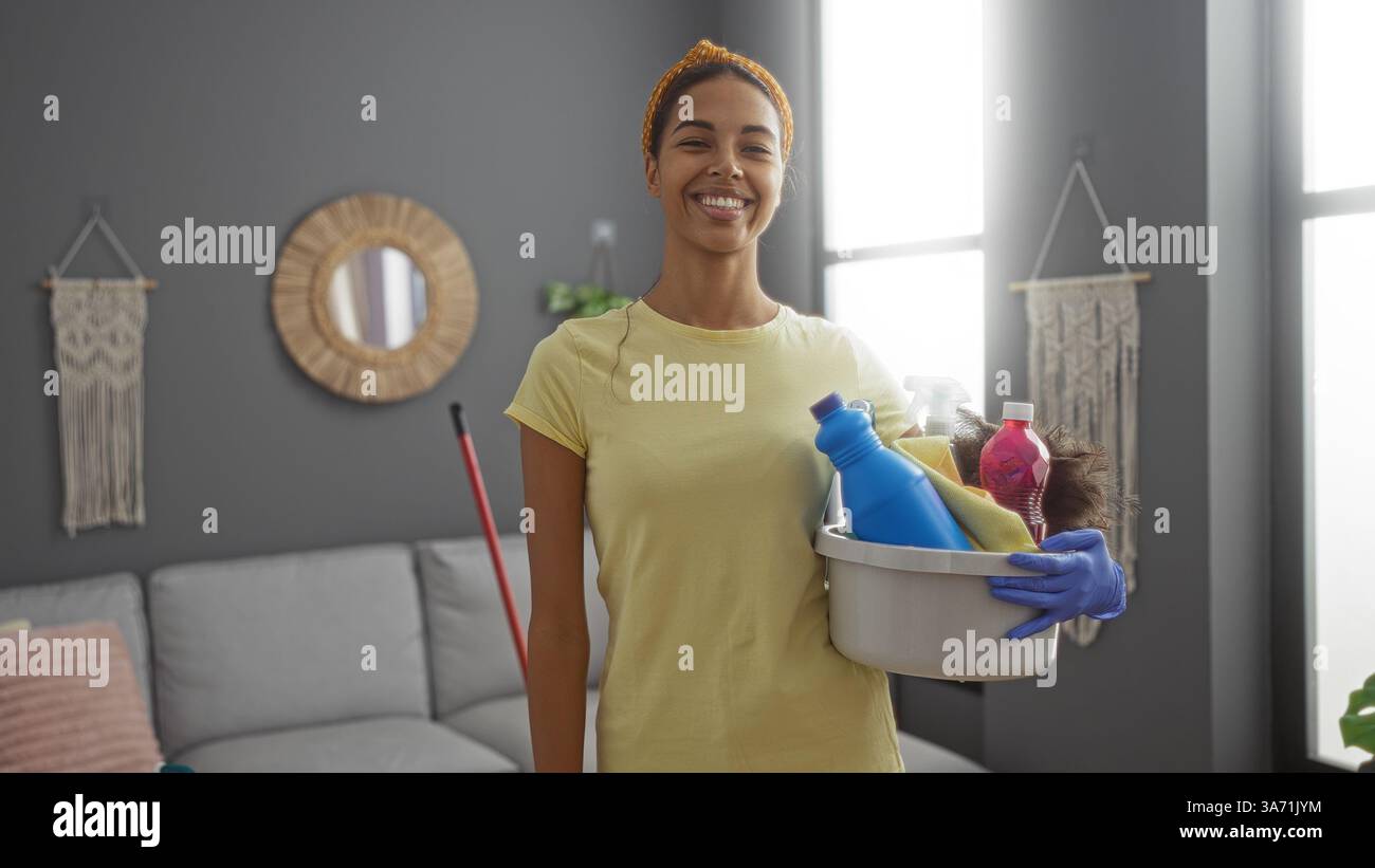 Woman smiling while holding cleaning supplies in a modern living room ...