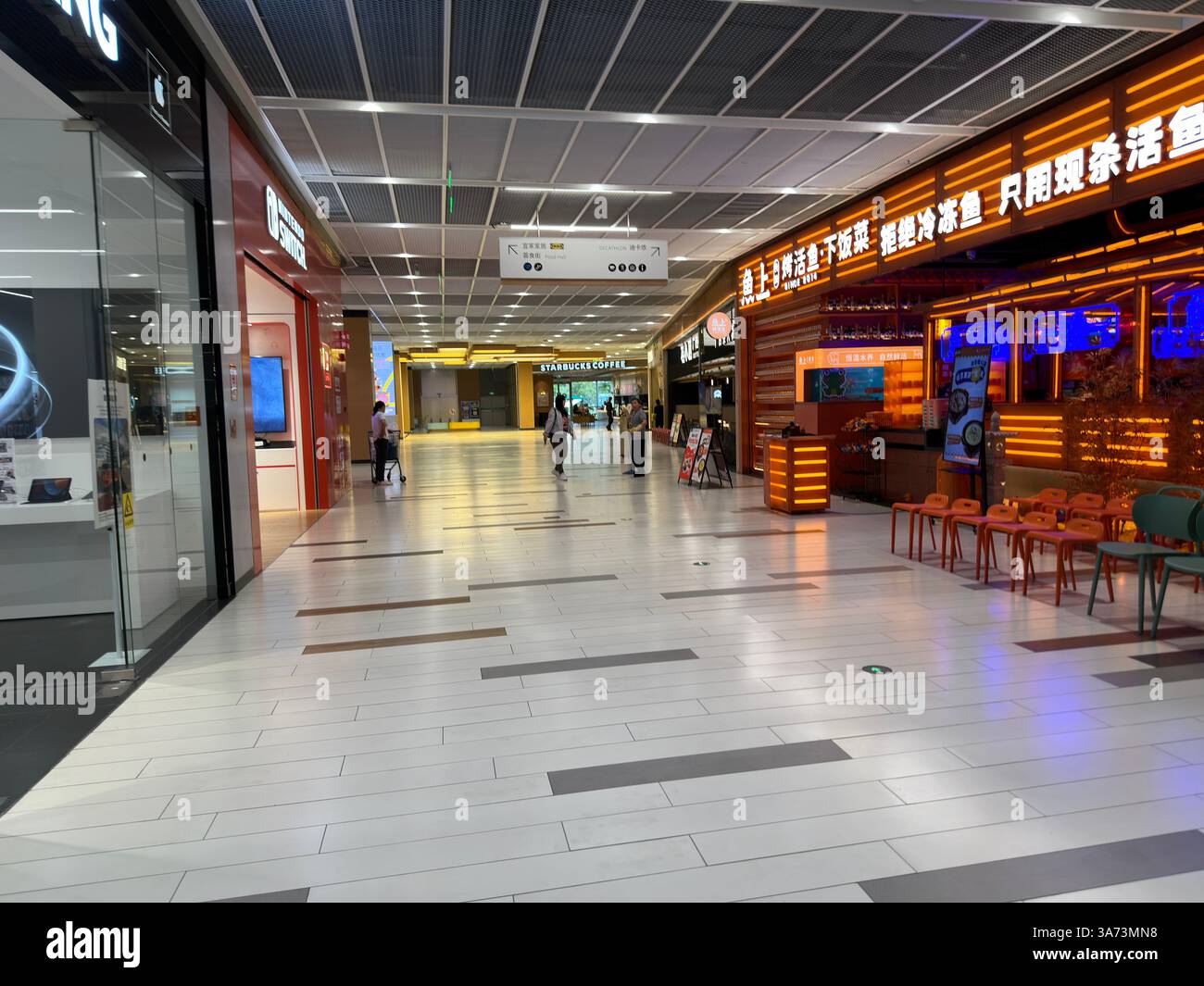 Nanning, Guangxi, China - Dec 2, 2023: A well-lit mall hallway with stores and restaurants. - Smartphone Captured Stock Image