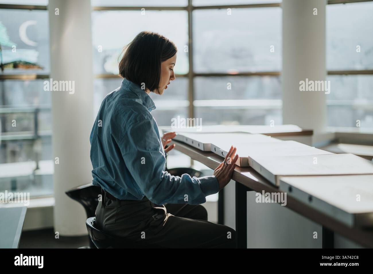 Young professional analyzing documents in modern office setting Stock Photo
