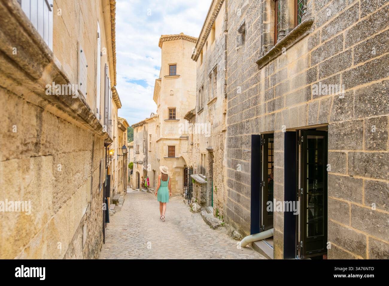 A young woman walks down a cobblestone lane in the medieval center of the French Village of Les Baux de Provence, France. Stock Photo
