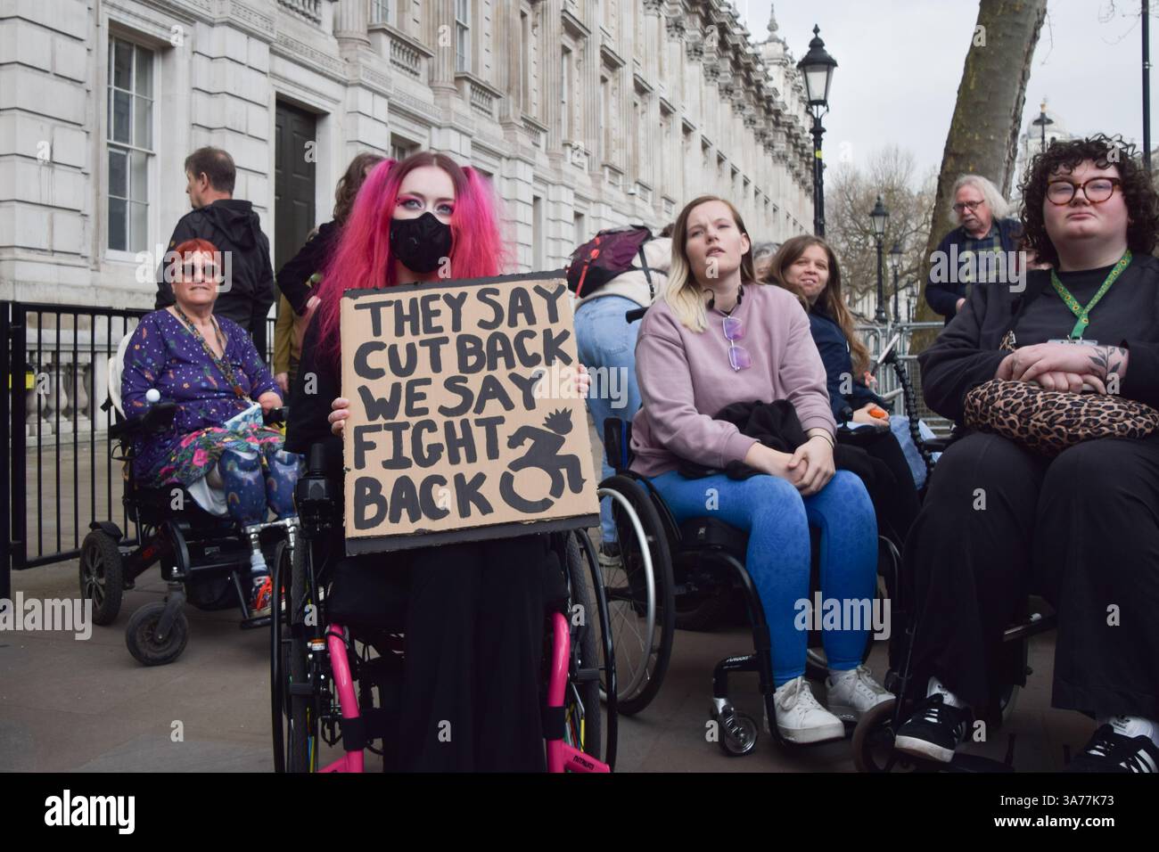 A protester holds a placard opposed to cuts outside Downing Street ...