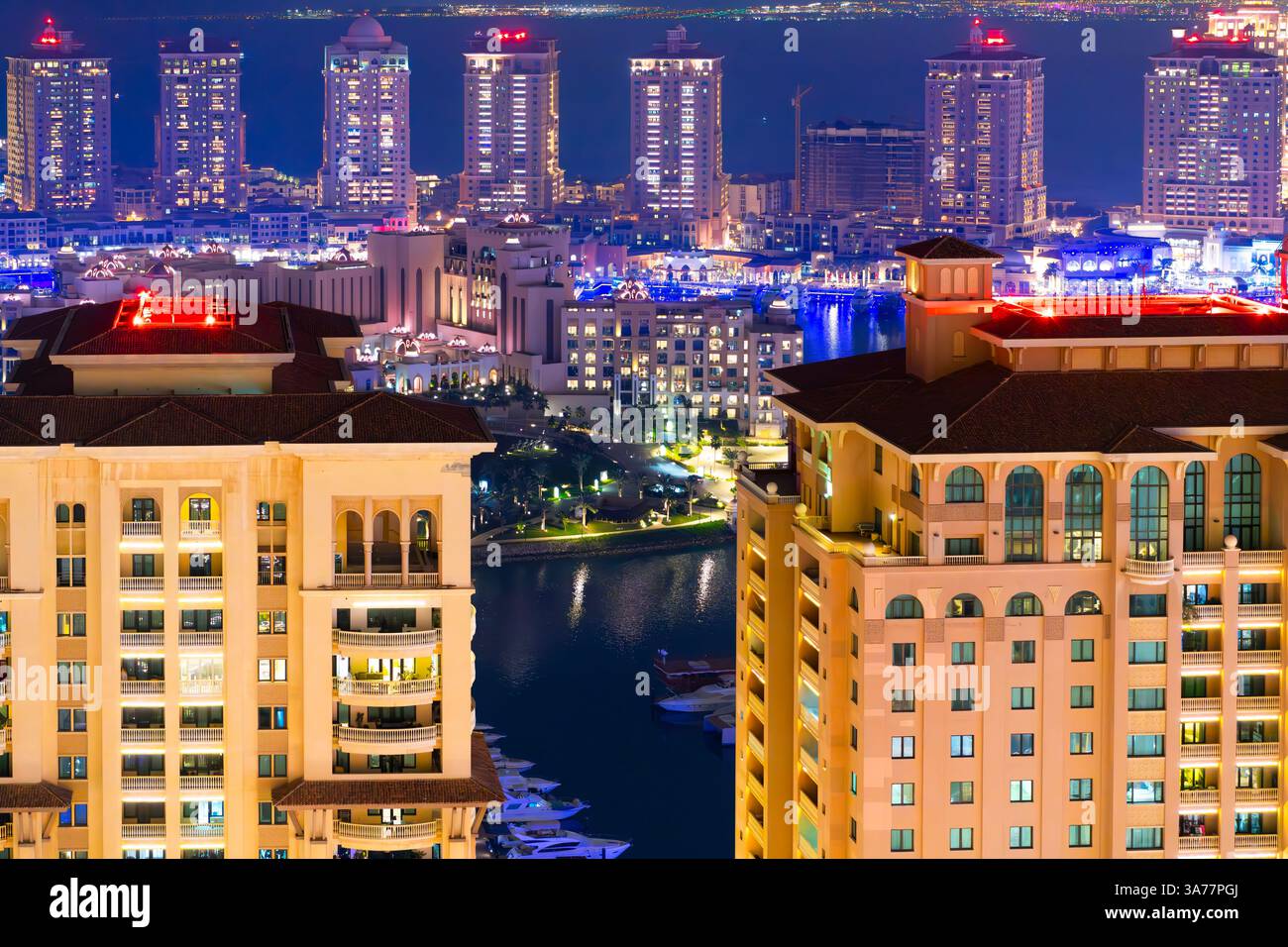 High angle night view of illuminated luxury buildings and waterfront marinas and shops at Doha Pearl Island along the Persian Gulf in Doha, Qatar. Stock Photo