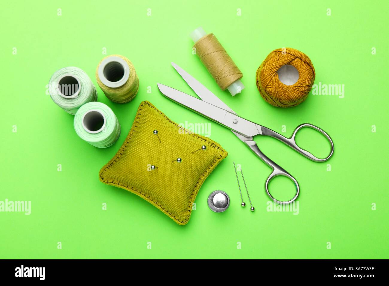 Different sewing supplies on green background, flat lay Stock Photo