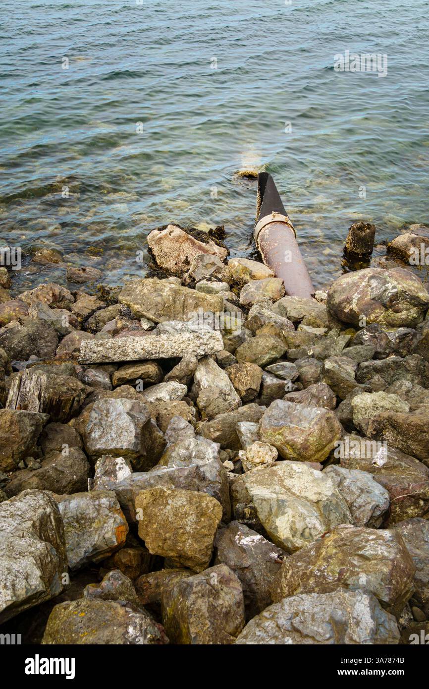 Storm sewer outlet, a pipe hidden under rocks discharging effluents and ...